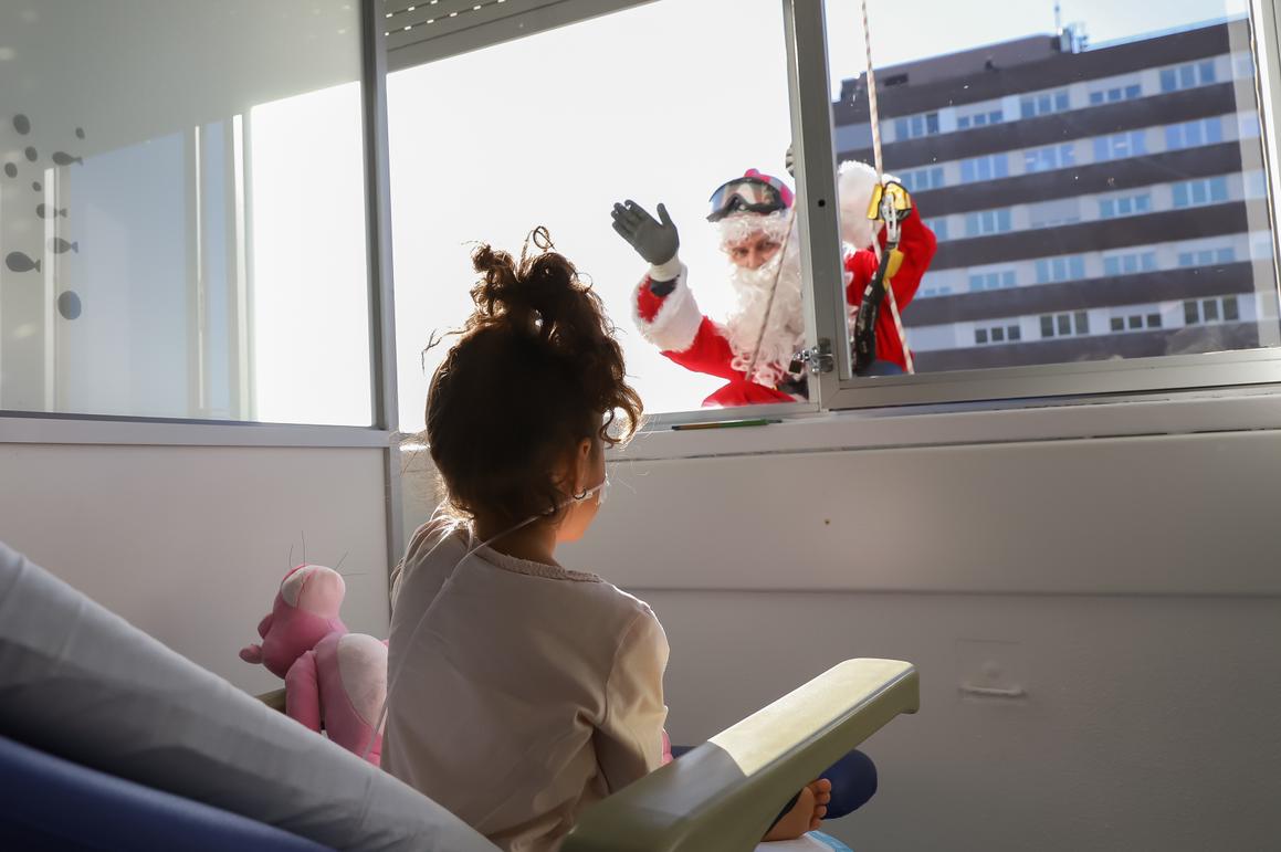 Una niña observa a Papá Noel en la ventana